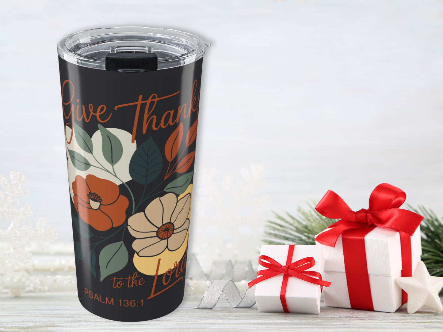 Black tumbler with floral design and text, placed next to gift boxes on a light background