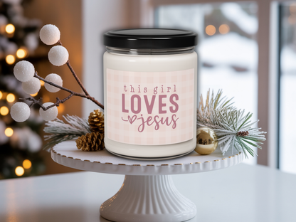 Candle with 'this girl LOVES Jesus' label on a white stand with decorative branches.