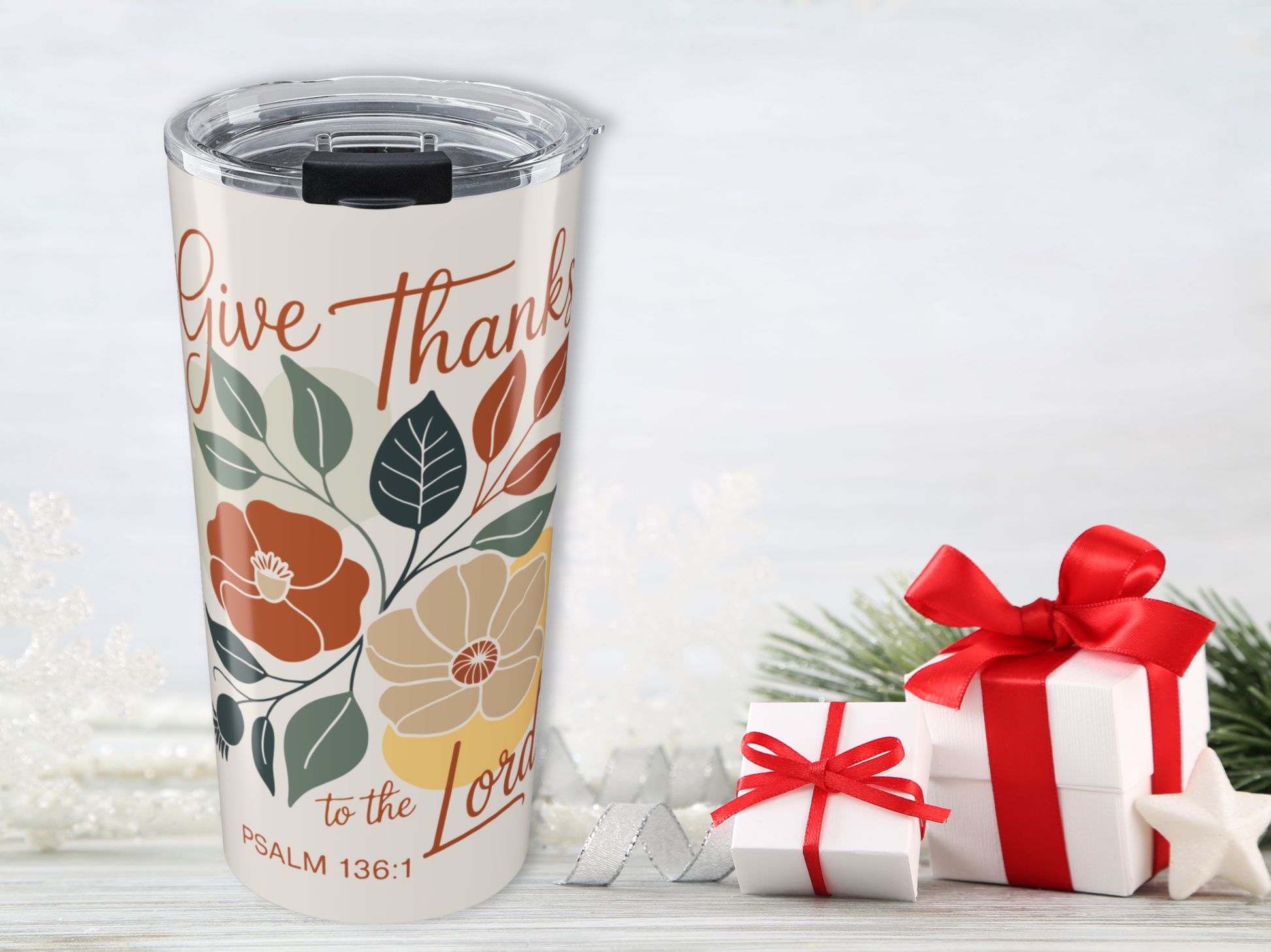 Tumbler with 'Give Thanks to the Lord' text and floral design, surrounded by Christmas presents on a white background.