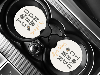 Two round coasters with text and graphics on a car cup holder