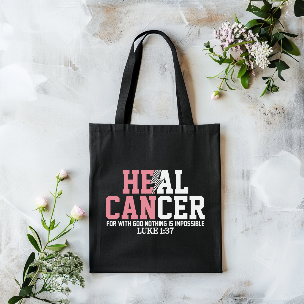 Black tote bag with 'HEAL CANCER' text on a light marble background with flowers.