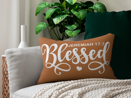 Brown lumbar pillow with “Blessed – Jeremiah 17:7” styled on a modern sofa with green cushion and cozy knit blanket.