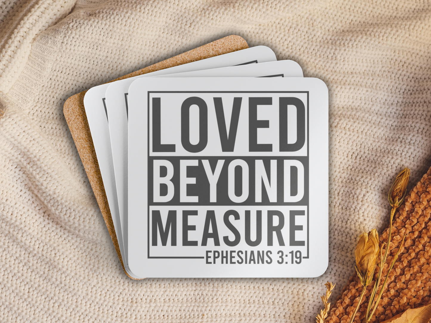 Coasters stacked on a cozy knitted blanket with dried florals, showcasing the cork backing.