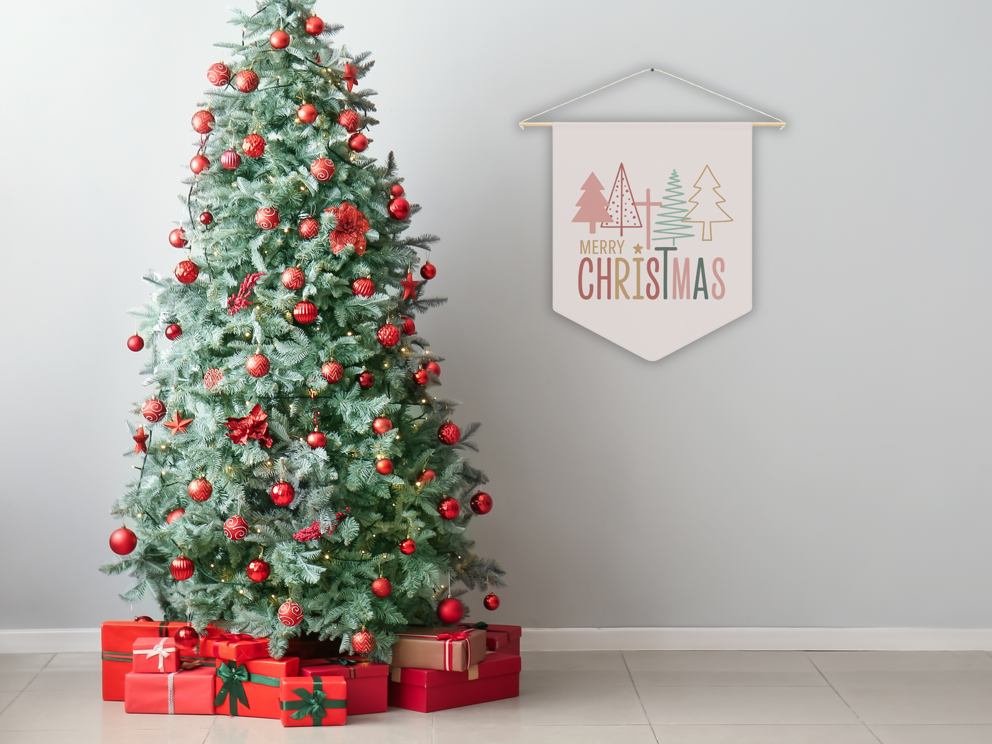 Decorated Christmas tree with red ornaments and presents underneath, against a plain wall with a 'Merry Christmas' sign.