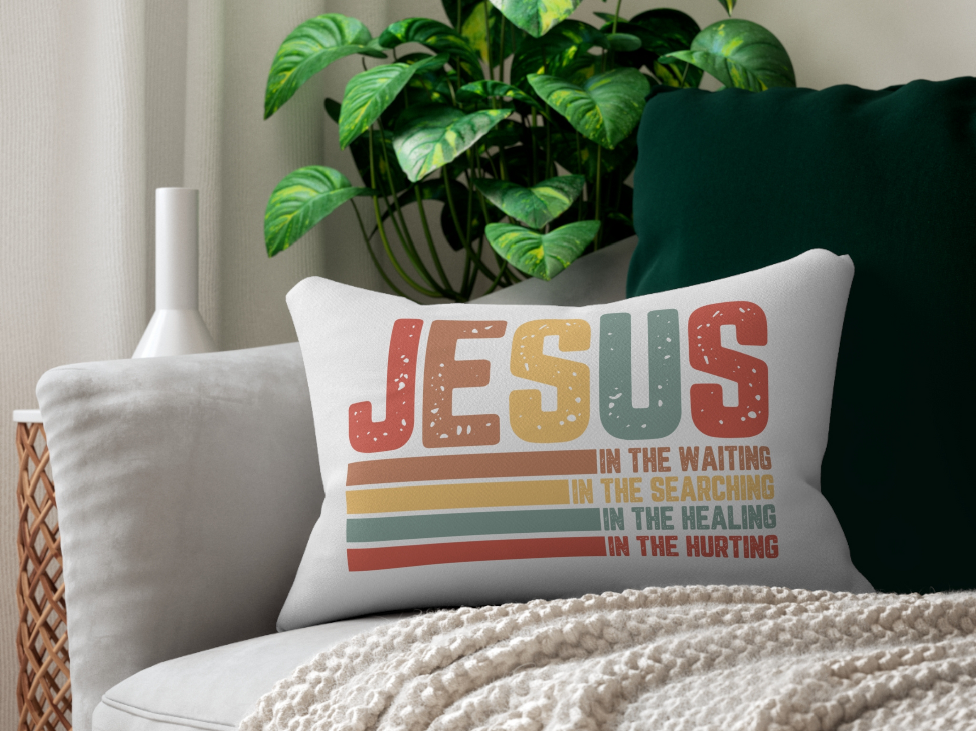 Pillow on a sofa with a green cushion, plant, and cozy throw blanket.