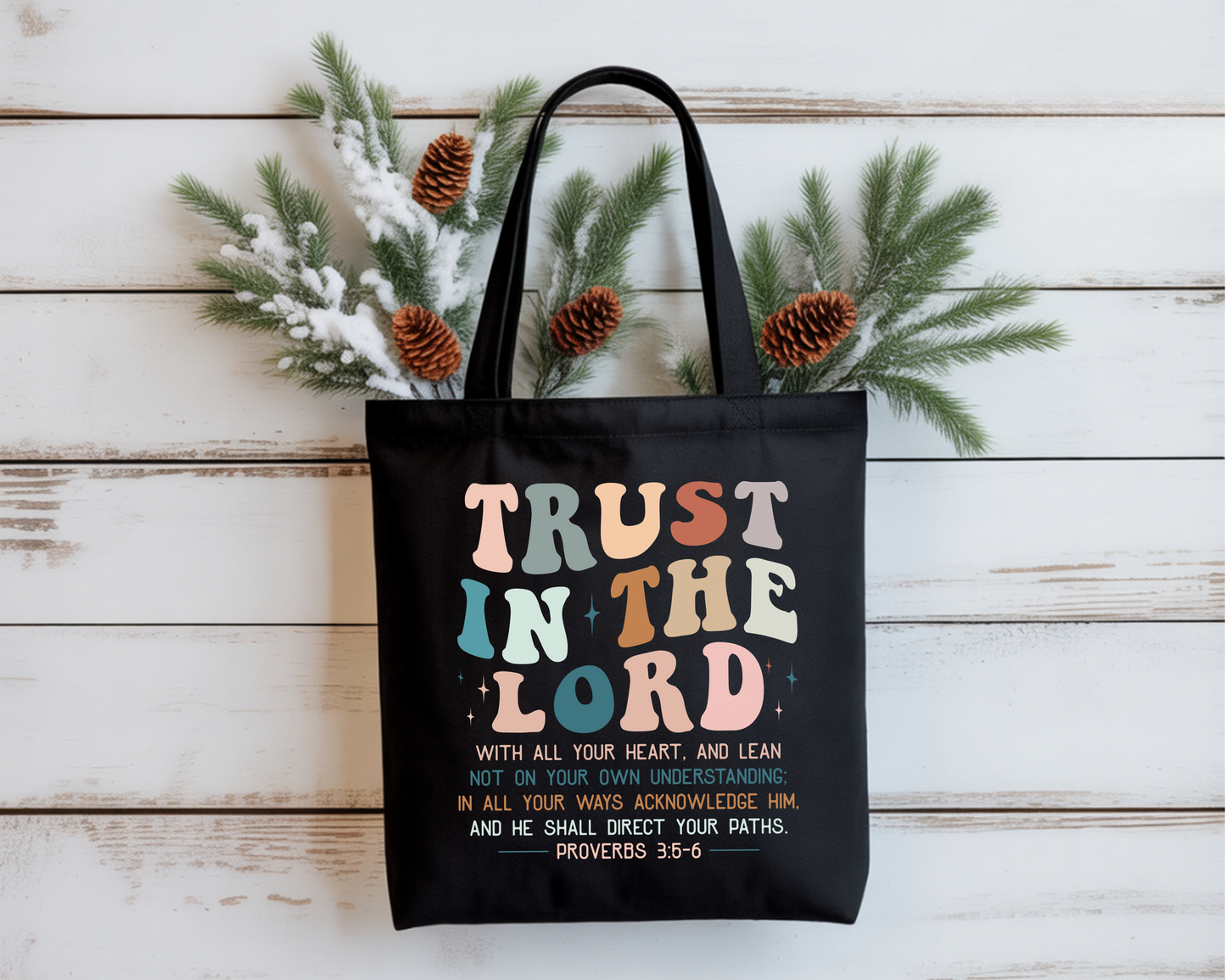 Black tote bag with colorful text on a wooden surface with decorative elements