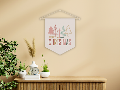 Decorative wall pennant  with 'Merry Christmas' text and trees hanging on a beige wall above a wooden cabinet.