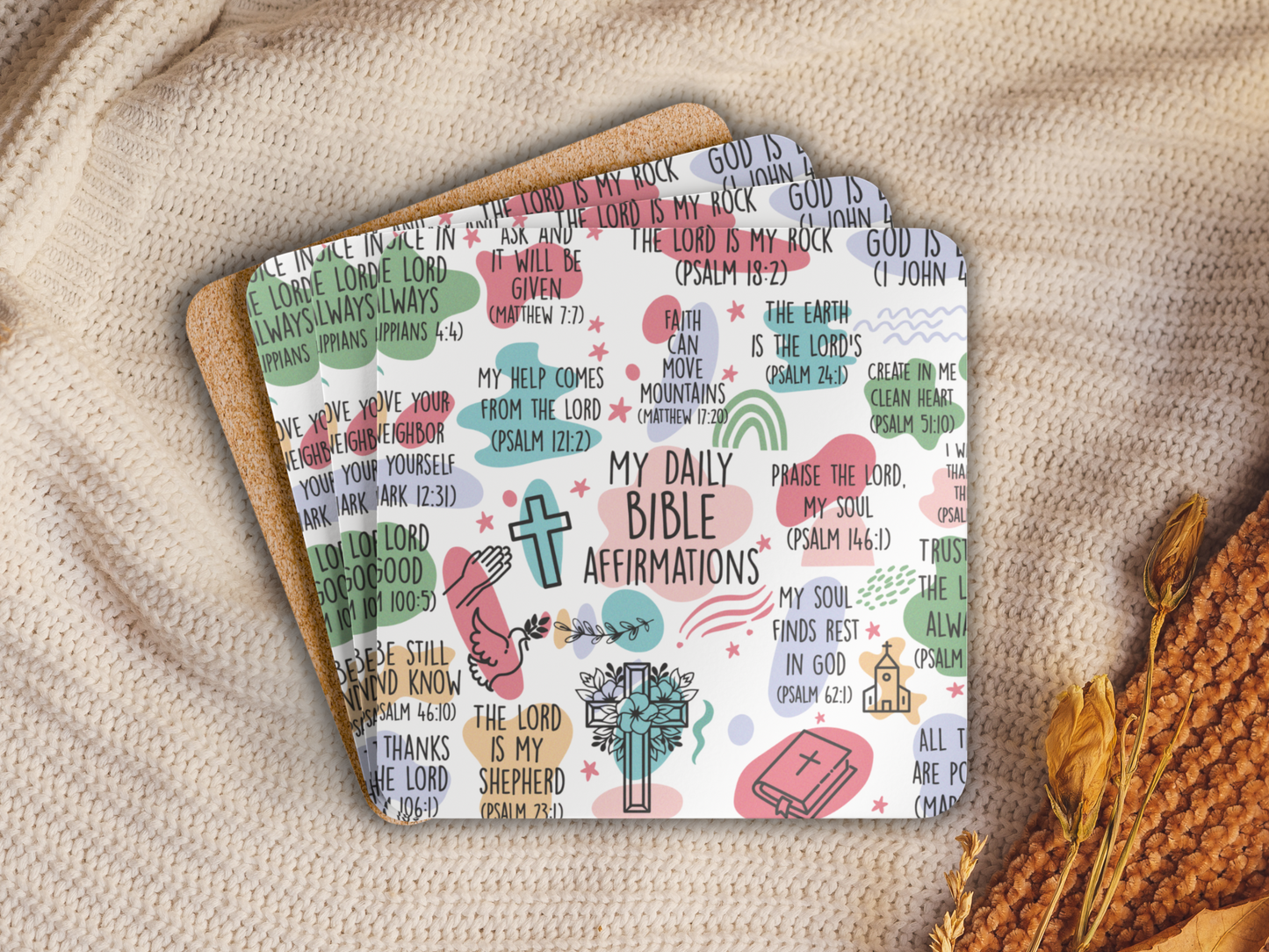 Stack of Bible affirmation coasters with cork backing, placed on a cozy knit blanket with dried flowers for a warm setting.