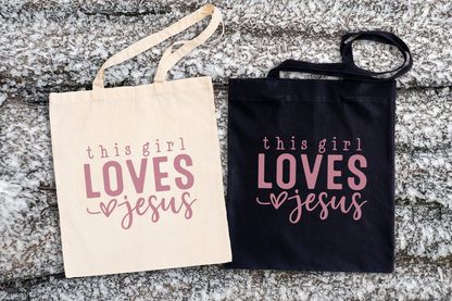 Two tote bags, one beige and one black, with 'this girl LOVES Jesus' text.