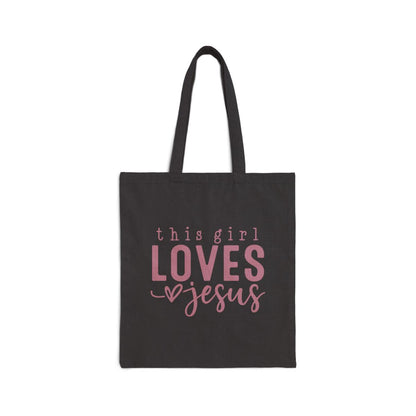 Black tote bag with pink text 'this girl LOVES Jesus' on a white background
