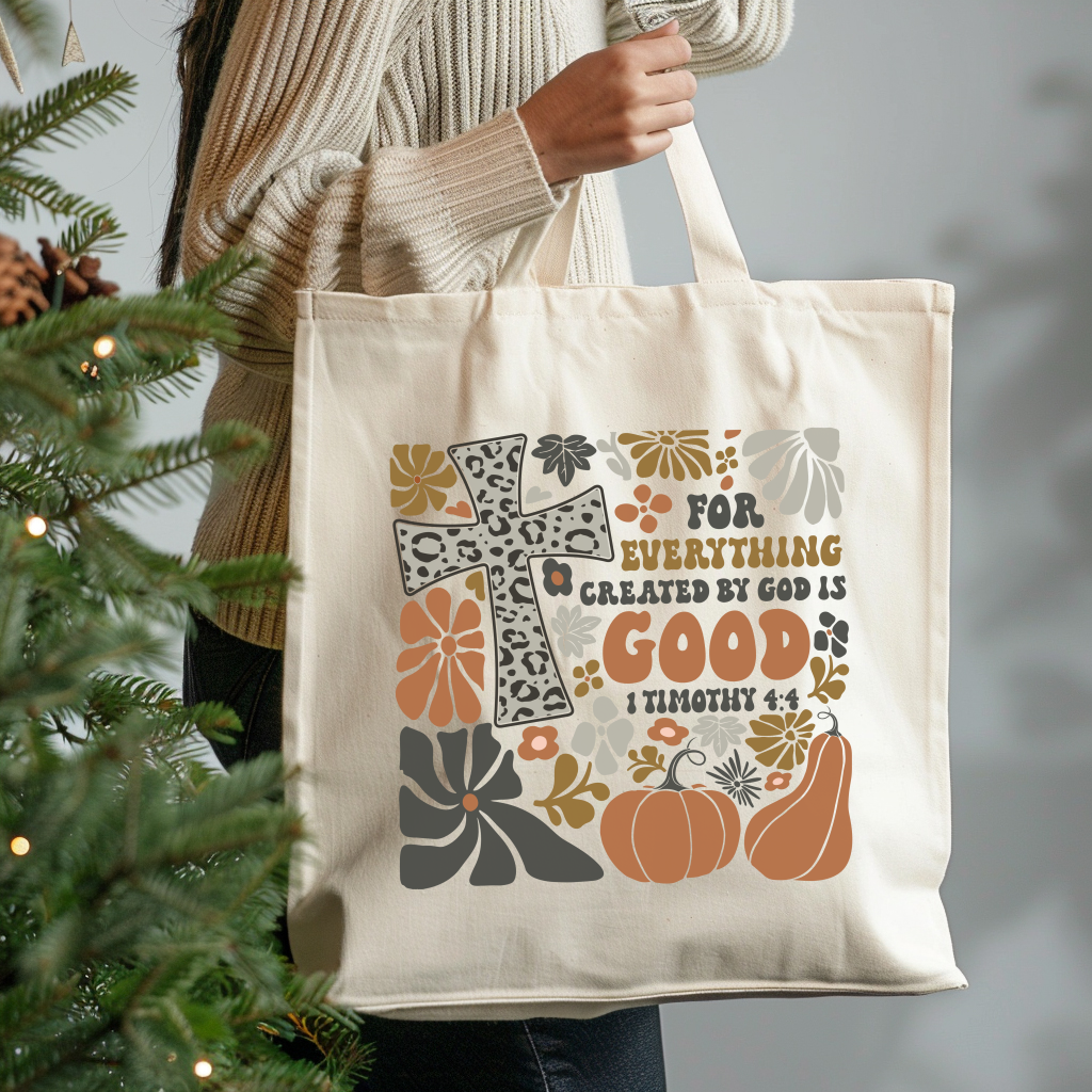 Tote bag with decorative design and text held by a person next to a Christmas tree.