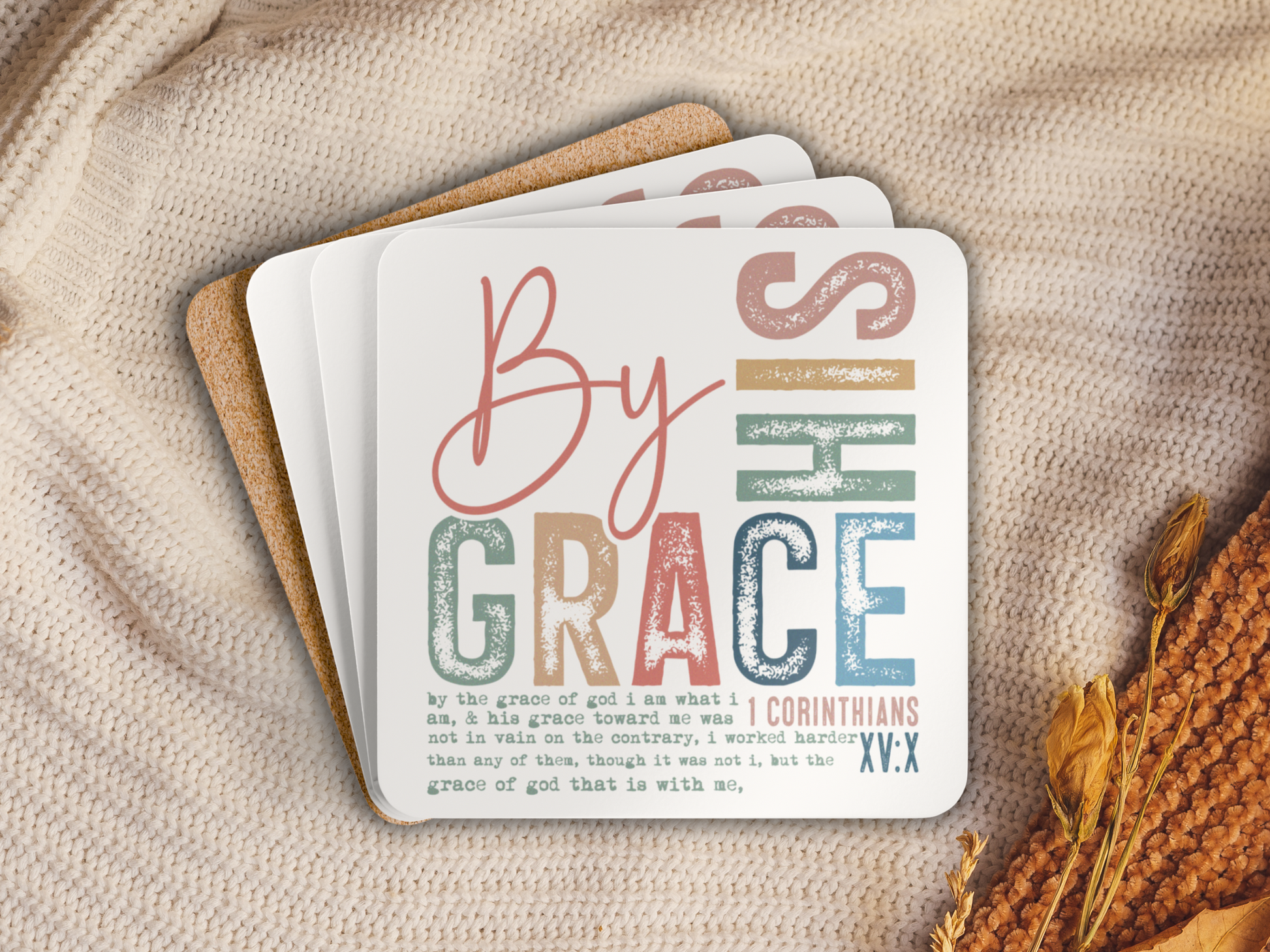 Stack of Bible verse coasters with cork backing placed on a cozy knit blanket with autumn accents.