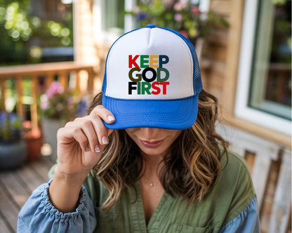 Person wearing a cap with 'KEEP GOD FIRST' text on a blurred outdoor background