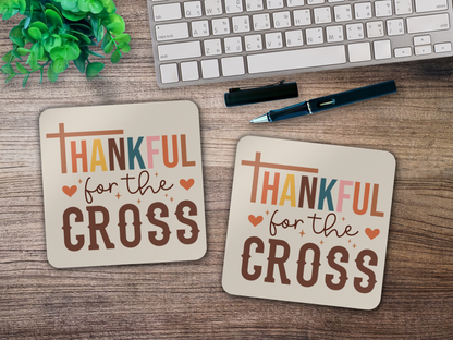 Two “Thankful for the Cross” coasters styled on a wooden desk with keyboard, pen, and green plant.