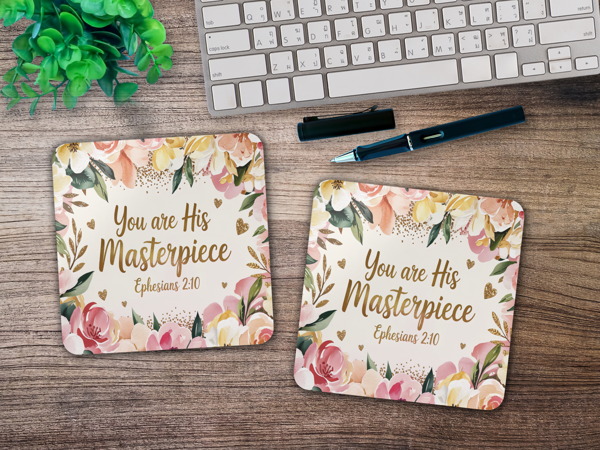 Two scripture coasters featuring floral border and gold lettering, styled on a wooden desk with keyboard, pen, and greenery.