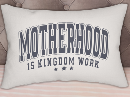 “Motherhood is Kingdom Work” pillow displayed against a tufted headboard with striped bedding.