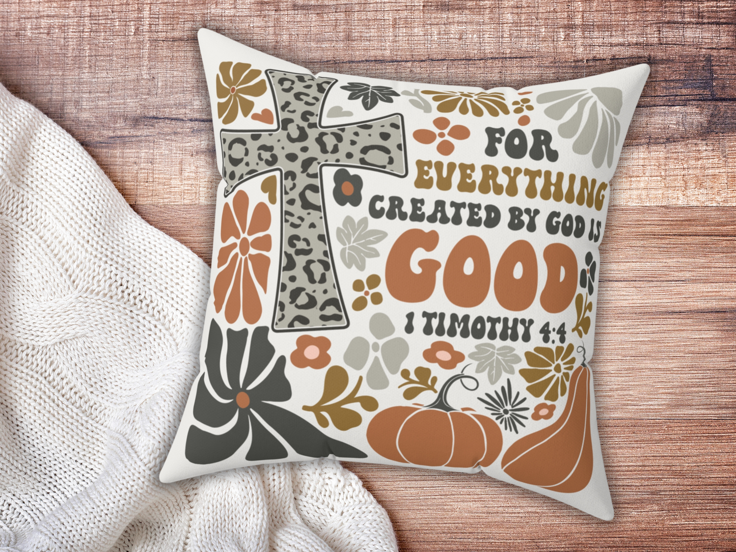 Christian decorative pillow with 1 Timothy 4:4 verse, leopard cross, pumpkins, and florals, displayed on wooden surface beside cream knit blanket.