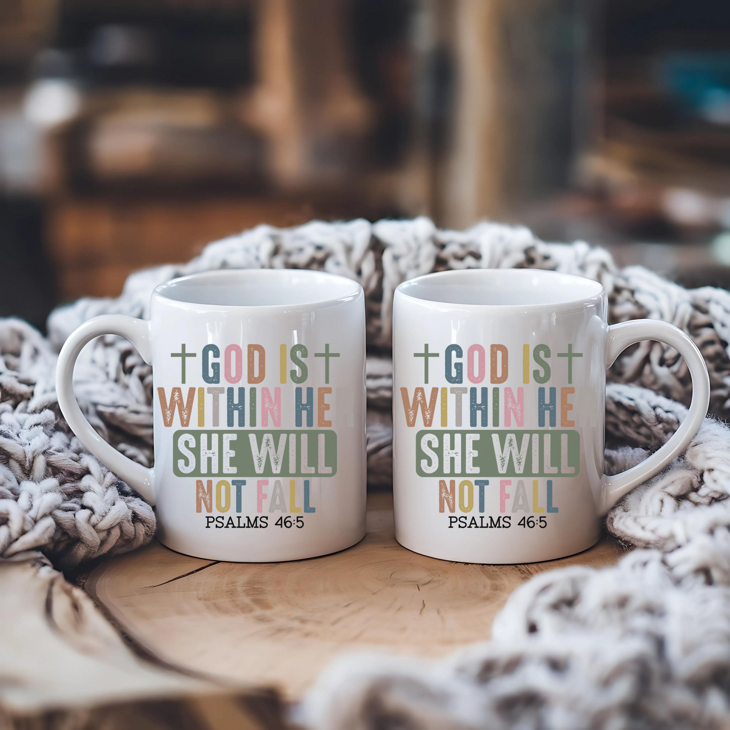 Two white mugs with motivational text on a wooden surface with a textured blanket.