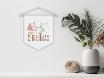 Decorative Christmas banner with trees and 'Merry Christmas' text, hanging on a white wall with plants and a vase below.