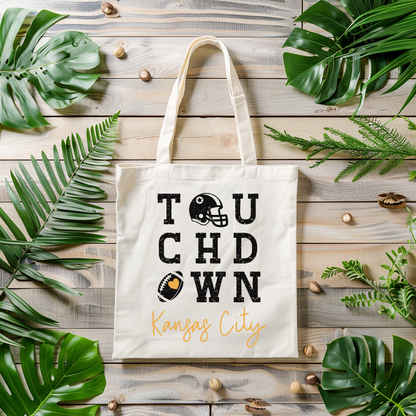 Tote bag with 'Touchdown Kansas City' design on a wooden surface with leaves