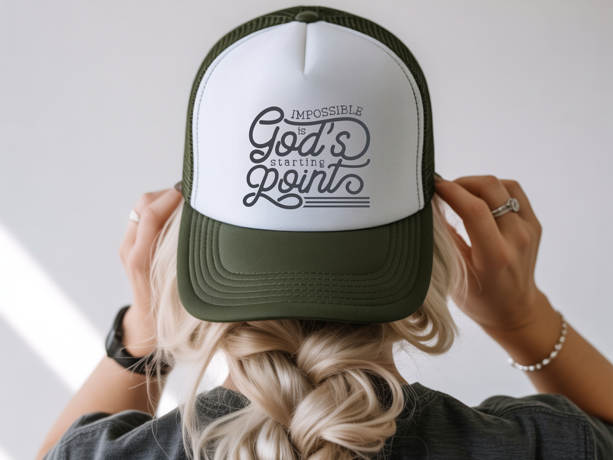 Person wearing a cap with 'Impossible is God's Point' text on a blurred background