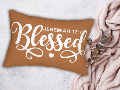 “Blessed” lumbar pillow displayed with a soft blush blanket and eucalyptus branch on a light surface.