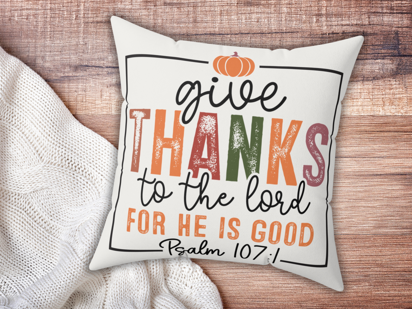 Scripture pillow on wooden surface paired with chunky white knit blanket.