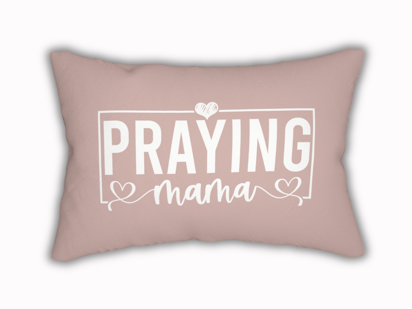 Rectangular blush pink pillow with white text design reading “Praying Mama” in bold and script font, accented with hearts.