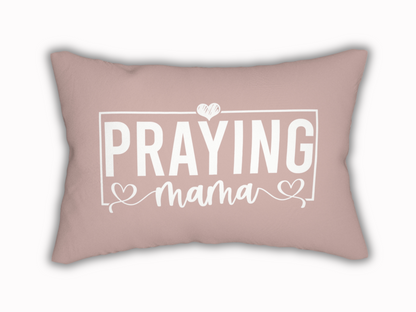 Rectangular blush pink pillow with white text design reading “Praying Mama” in bold and script font, accented with hearts.