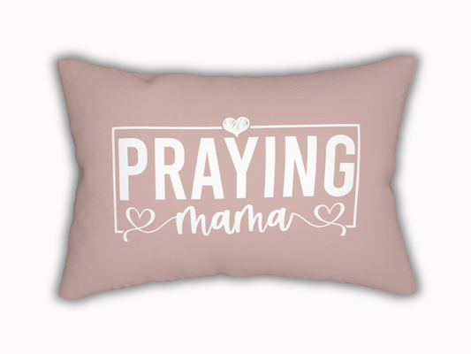 Rectangular blush pink pillow with white text design reading “Praying Mama” in bold and script font, accented with hearts.